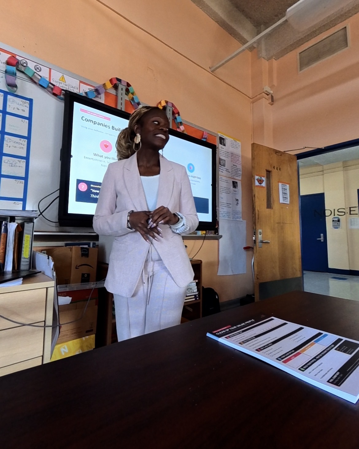 Schnelle teaching at the front of a classroom, smiling while presenting