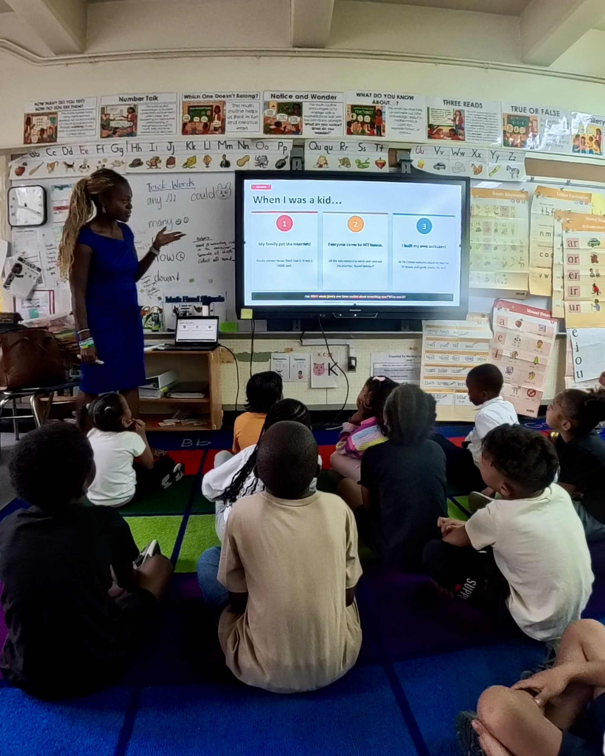 Schnelle Acevedo animatedly teaching a digital literacy lesson in front of a classroom smartboard