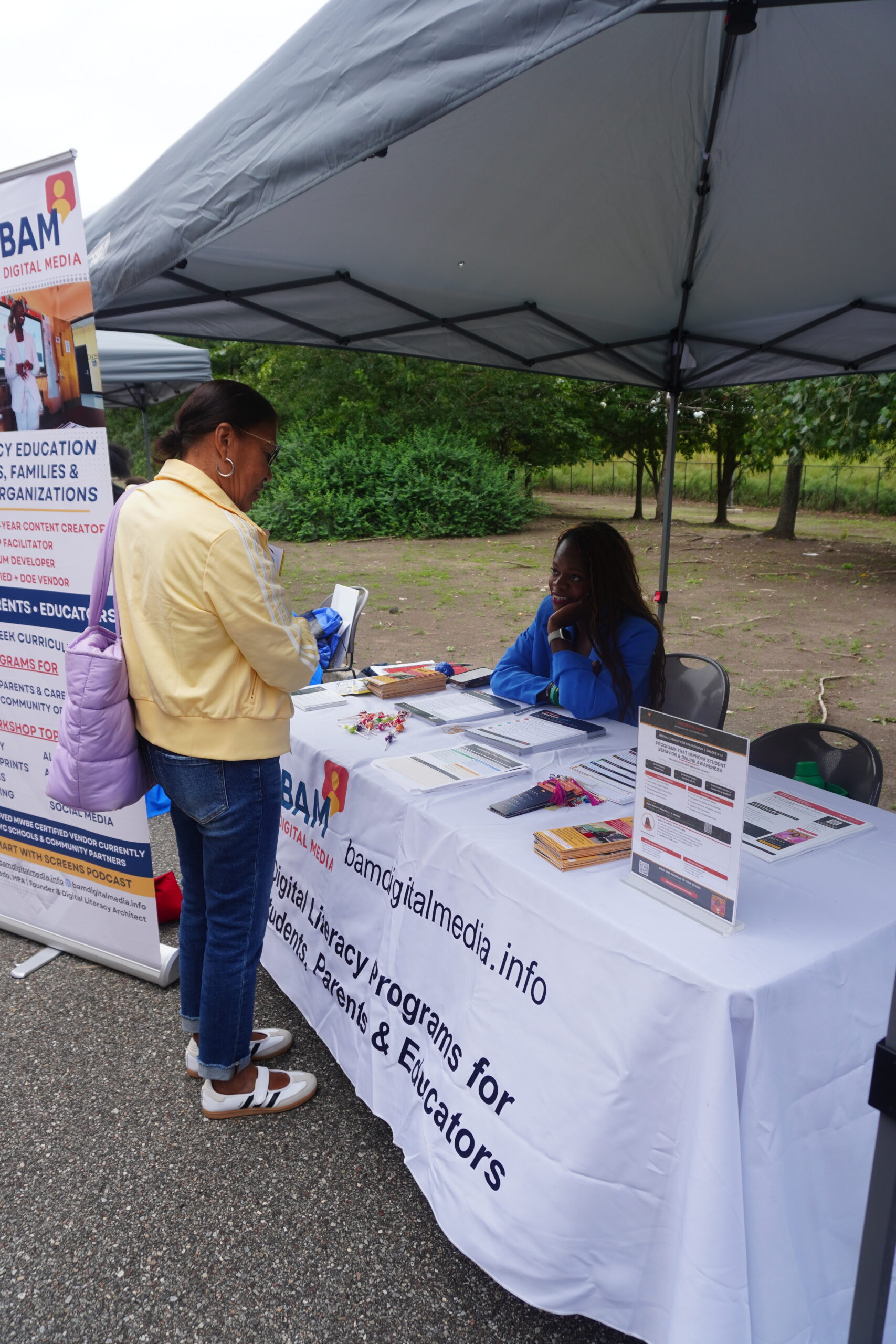 A neighbor stops by the BAM Digital Media table to talk with Schnelle Acevedo
