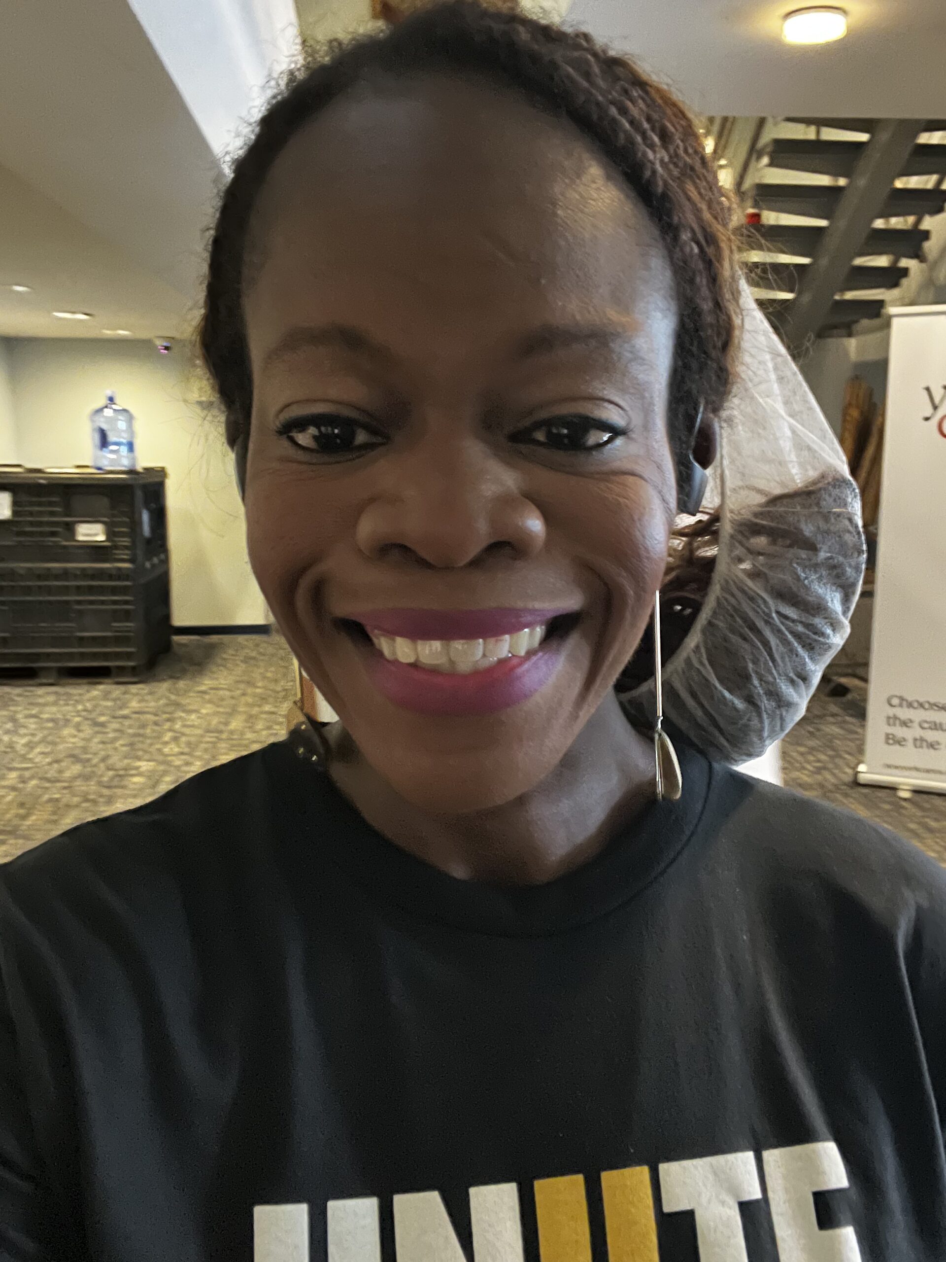 Schnelle Acevedo smiling in a UNIITE For Good volunteer shirt and hairnet